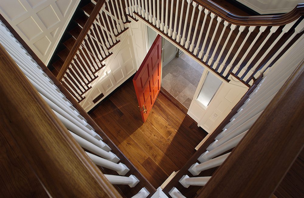 Looking down a beautiful staircase, with warm toned wood and painted white accents